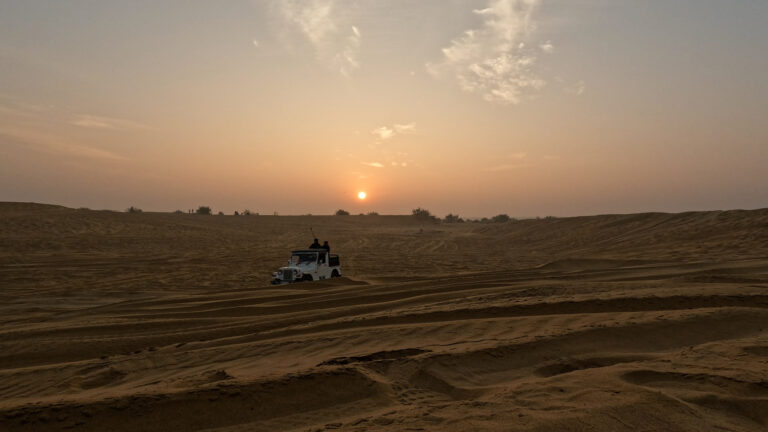 Wide shot of a 4x4 jeep parked on the sand dunes of the Thar Desert during a beautiful golden sunrise in Jaisalmer. Golden hour in the Thar Desert. The adventure begins. #Jaisalmer #Sunrise #IncredibleIndia