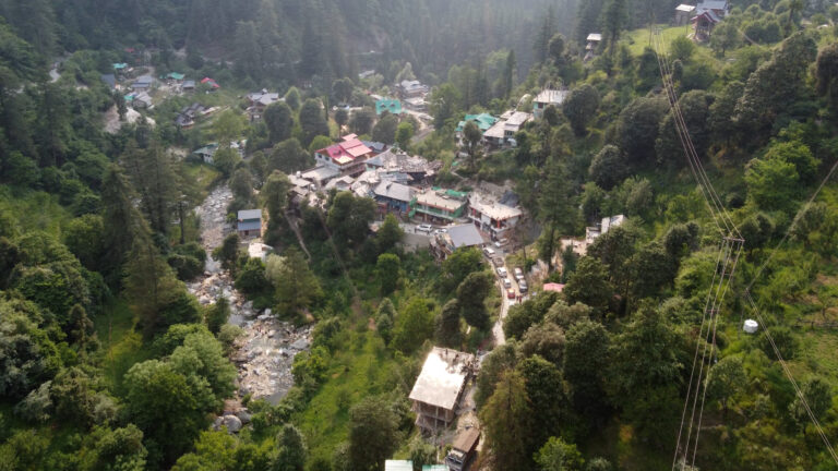 Aerial drone shot of Jibhi village surrounded by Himalayan pine forests and green valleys in Himachal Pradesh